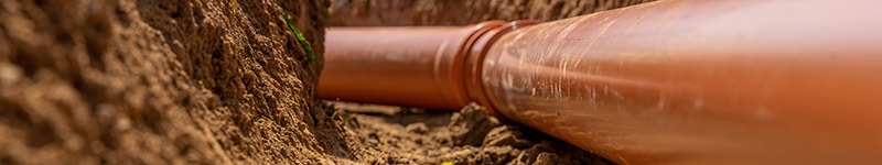 pipes being placed in a trench in the ground